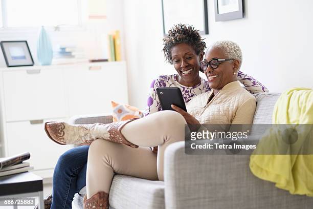 smiling women using tablet in living room