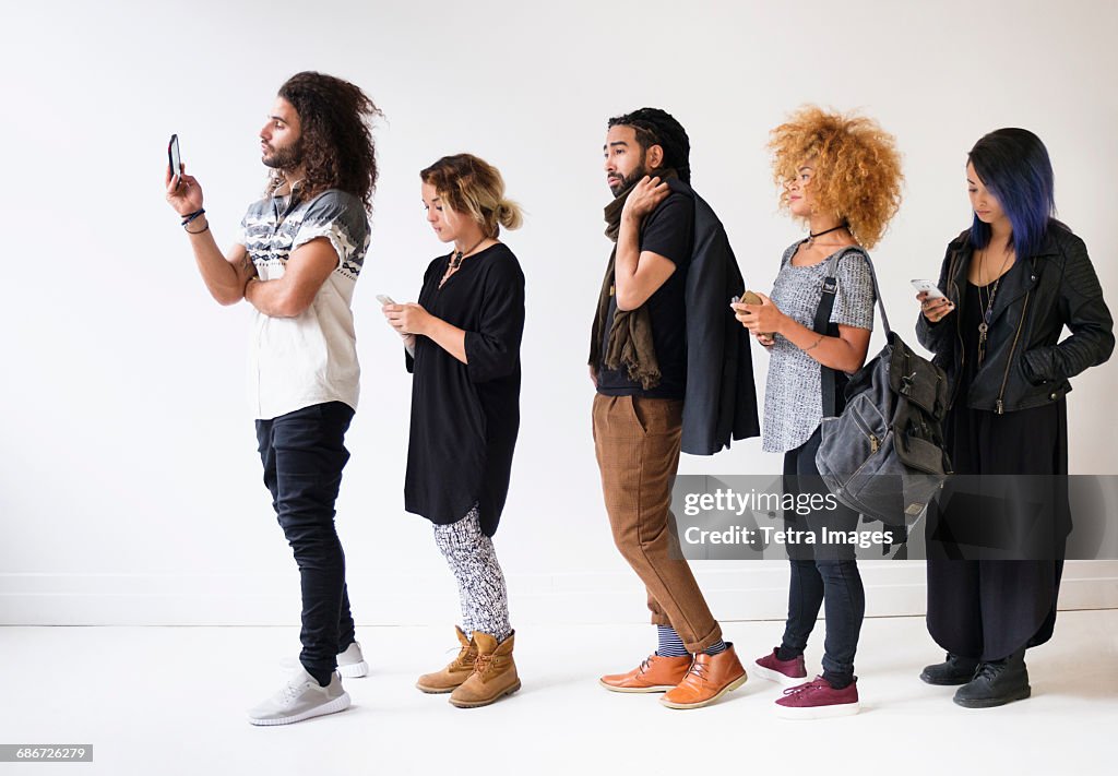 Young people standing in line using smartphones