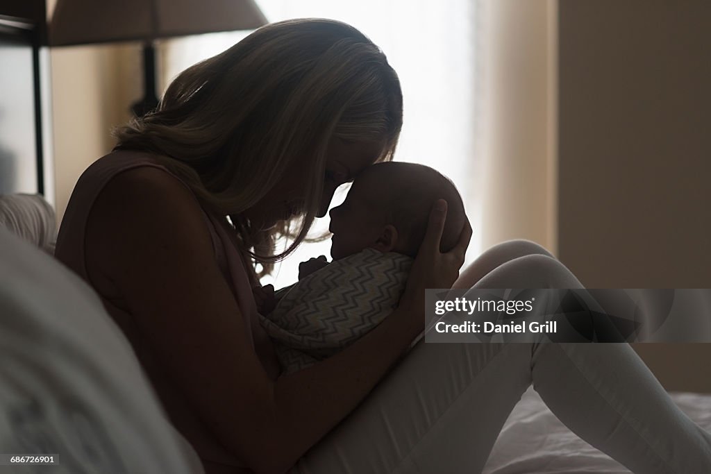 Mother holding son (0-1 months) in bedroom