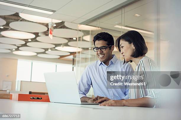 businessman and woman using laptop together - asian and indian ethnicities fotografías e imágenes de stock