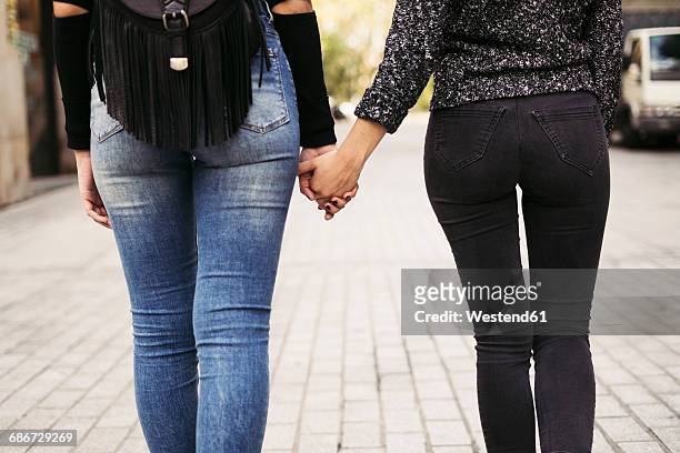 back view of two women holding hands on the street - buttocks gay stock pictures, royalty-free photos & images