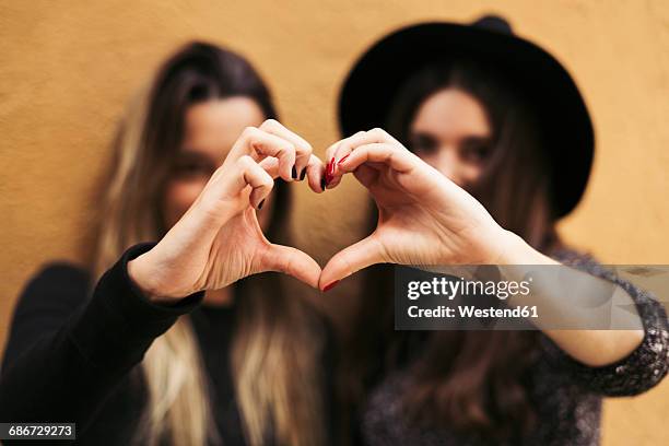 two women shaping hands to a heart - handen over elkaar stockfoto's en -beelden