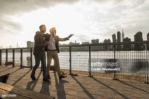 usa, new york city, two businessmen walking together along east river - panorama nyc day 2 foto e immagini stock