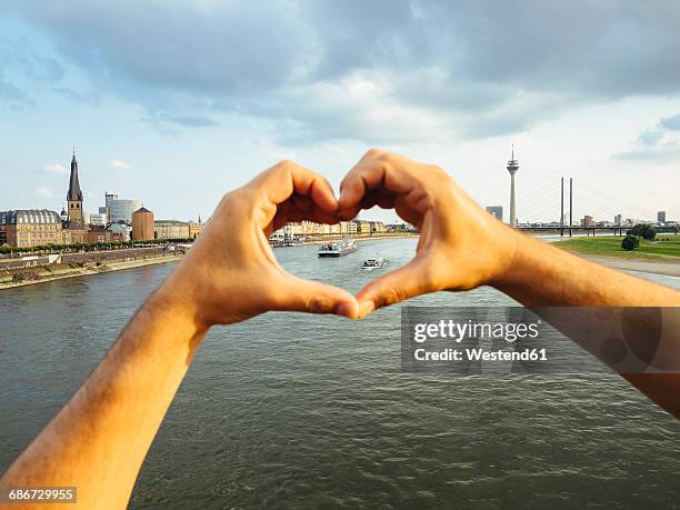 germany, duesseldorf, hands forming a heart framing ships on rhine river - rhein stock-fotos und bilder