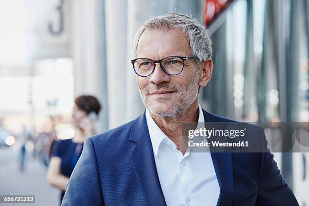 confident businessman outdoors with woman in background - man expressive background glasses stock pictures, royalty-free photos & images