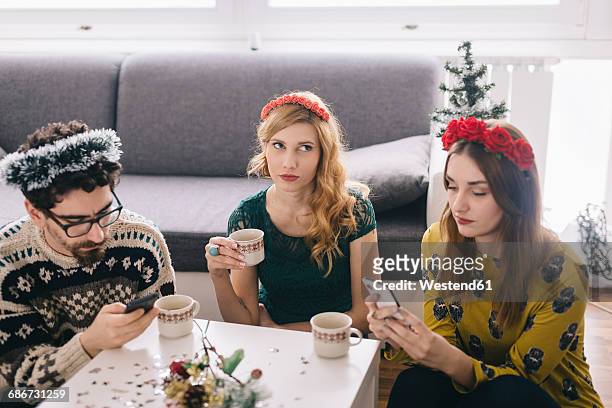 annoyed young woman sitting between her friends looking at her smartphones - social exclusion stock pictures, royalty-free photos & images