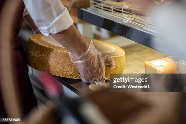 grocer with cheese wheel, partial view - cheese stock pictures, royalty-free photos & images