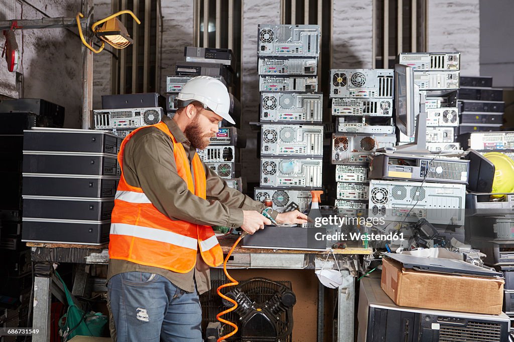 Worker in computer recycling plant cleaning pc casing