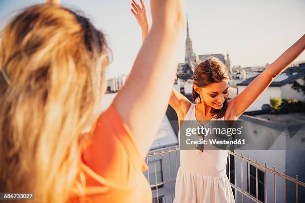 austria, vienna, two women dancing on roof terrace - nur frauen balkon stock-fotos und bilder