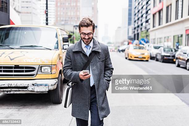 usa, new york city, smiling businessman with cell phone on the go - ragazzo new york foto e immagini stock