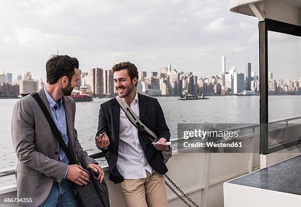 usa, new york city, two smiling businessmen talking on ferry on east river - ferry passenger stock pictures, royalty-free photos & images