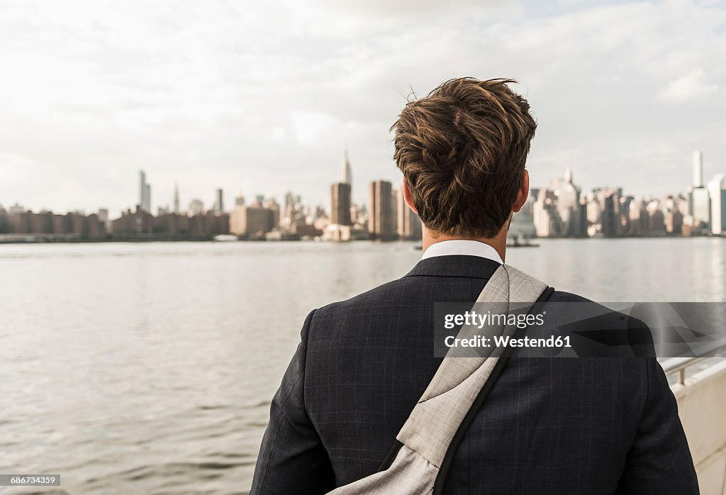 USA, New York City, back view of man at East River looking on Manhattan