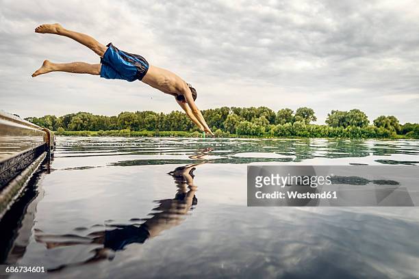 man jumping from jetty into water - sprung ins wasser stock-fotos und bilder