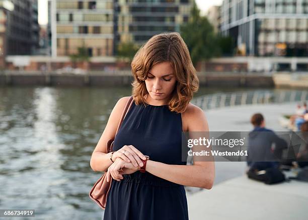germany, hamburg, young woman looking at watch - reloj de pulsera fotografías e imágenes de stock