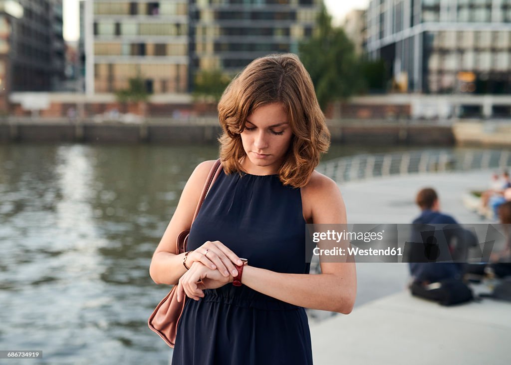 Germany, Hamburg, Young woman looking at watch