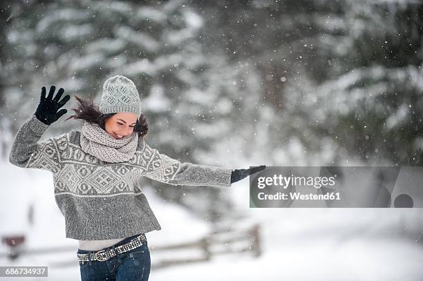 happy woman wearing knitwear dancing in the snow - halstuch stock-fotos und bilder