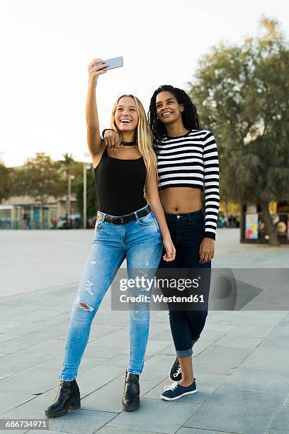 two young women taking a selfie on square - 自分撮り ストックフォトと画像