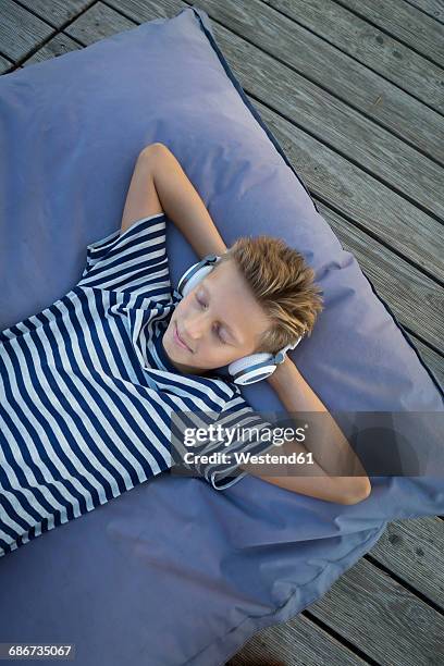 boy lying on beanbag listening music with headphones - bean bags fotografías e imágenes de stock