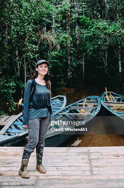 peru, tambopata, woman with muddy rubber boots standing on jetty at amazon river - wellington boot stockfoto's en -beelden