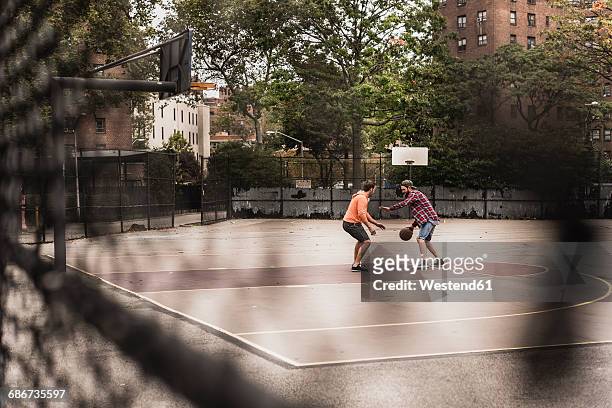 two young men playing basketball on an outdoor court - streetball stock pictures, royalty-free photos & images