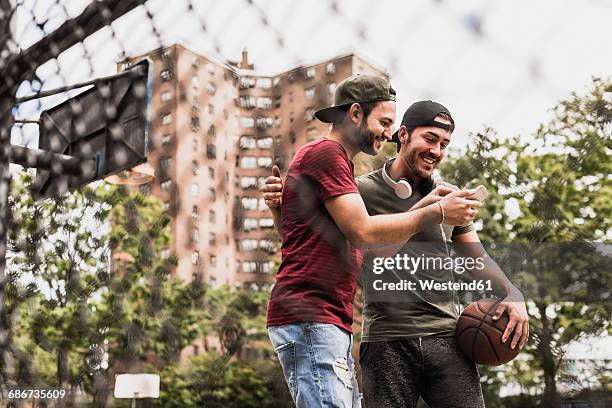 two smiling friends with basketball and cell phone outdoors - fences 2016 film stock-fotos und bilder