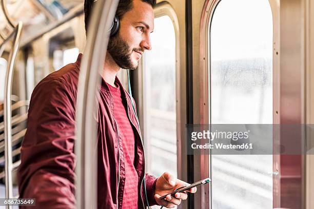 young man in subway wearing headphones - new york subway train fotografías e imágenes de stock