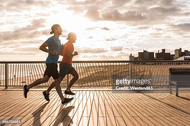 usa, new york city, two men running on coney island - young man jogging stock pictures, royalty-free photos & images
