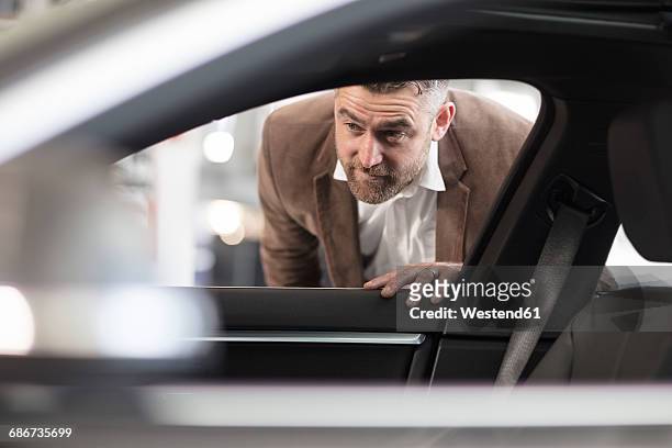 man looking into car in car dealership - car review foto e immagini stock