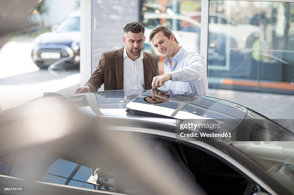 Car dealer talking to client at car dealership