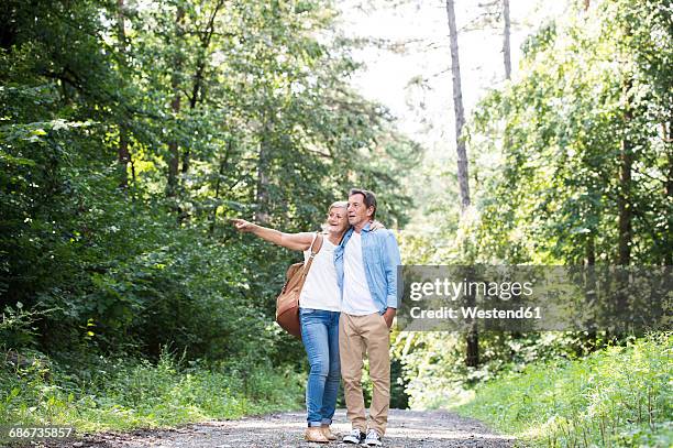 senior couple standing on forest track watching something - couple looking sideways stock pictures, royalty-free photos & images