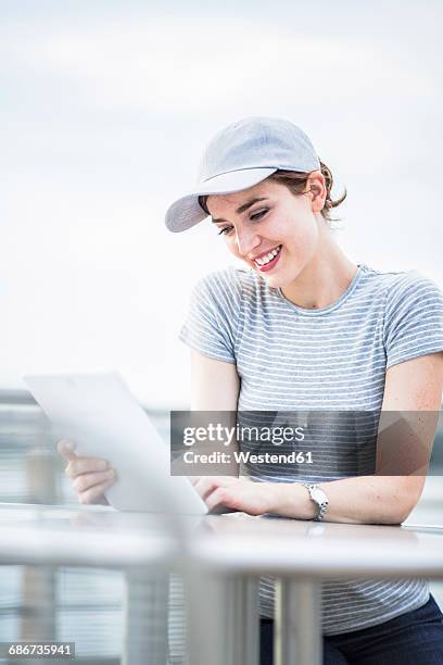 smiling woman with basecap looking at tablet - basecap stock pictures, royalty-free photos & images