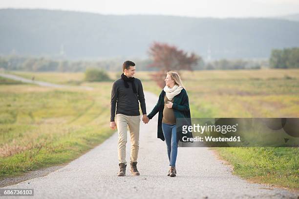 happy expectant parents walking in rural landscape - pregnant couple stock pictures, royalty-free photos & images