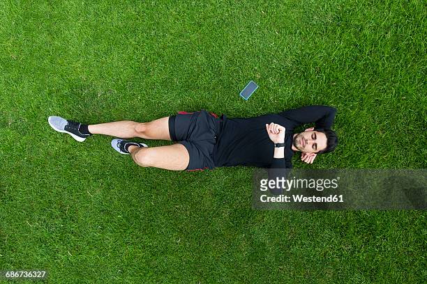 jogger lying in grass looking on watch - reclining stock pictures, royalty-free photos & images