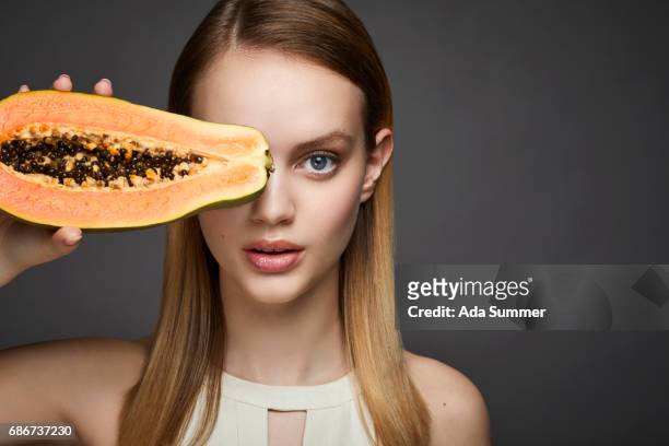 studio shot of a beautiful young woman holding a papaya - papaya stock pictures, royalty-free photos & images