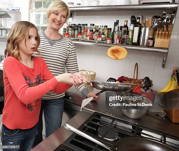 "mother and daughter in kitchen, daughter flipping pancake" - pancake toss stock-fotos und bilder