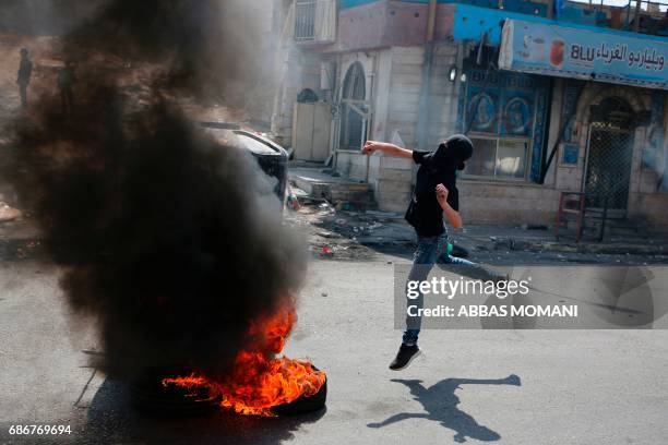 Masked Palestinian protester throws a stone towards Israeli troops during a protest by Palestinians in support of prisoners refusing food in Israeli...