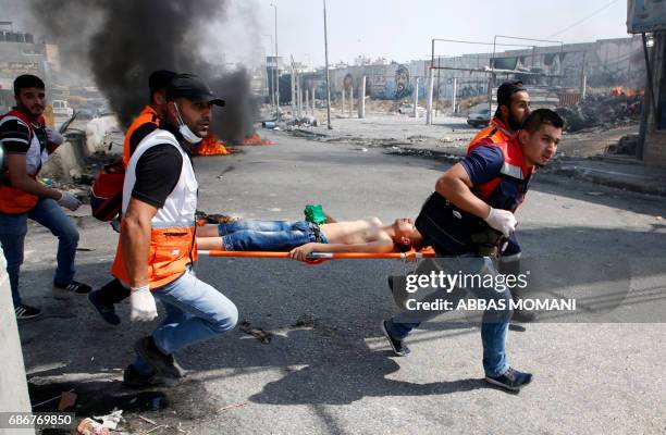 Palestinian medics evacuate a wounded protester during clashes with Israeli troops following a protest by Palestinians in support of prisoners...