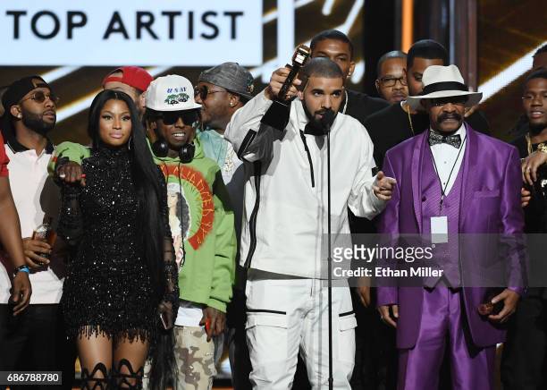 Rappers Nicki Minaj and Lil' Wayne look on as recording artist Drake accepts the Top Artist award onstage with his father Dennis Graham during the...
