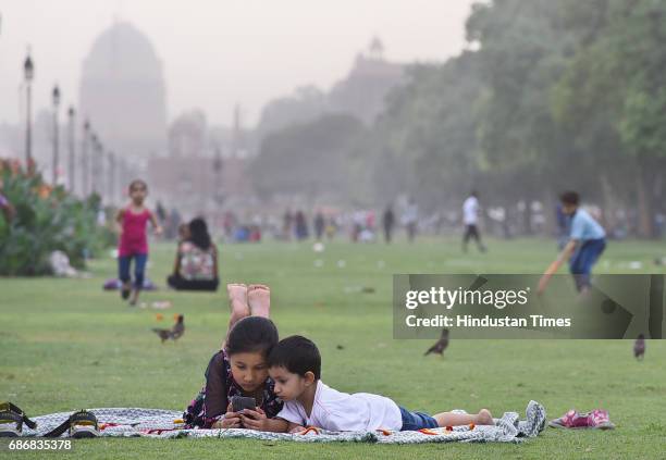 Kids busy on a phone in India Gate lawn on a cloudy day on May 22, 2017 in New Delhi, India. Rain in Delhi brings mercury 10 degree below normal,...