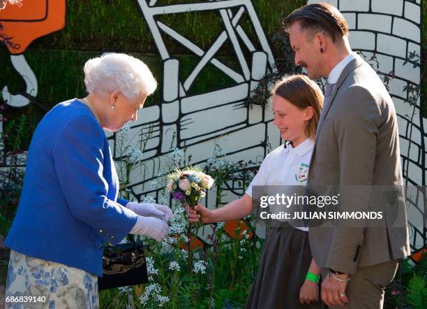 Britain's Queen Elizabeth II reacts as is present with a posy of flowers by Caitlyn James from Swansea at the Chelsea Flower Show in London on May...