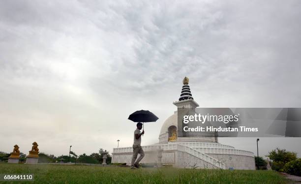 Man walking with an umbrella in a cloudy morning at replica of Shanti Stupa on May 22, 2017 in New Delhi, India. Rain in Delhi brings mercury 10...