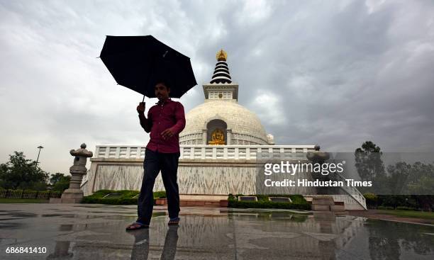 Man walking with an umbrella in a cloudy morning at replica of Shanti Stupa on May 22, 2017 in New Delhi, India. Rain in Delhi brings mercury 10...