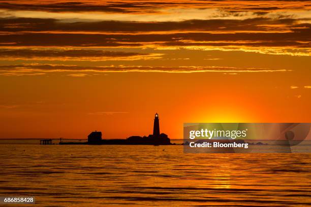 The sun rises behind the Boston Light on Little Brewster Island off of Hull, Massachusetts, U.S., on Wednesday, May 17, 2017. New restrictions are...