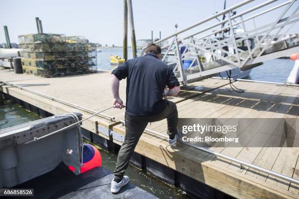 Deckhand pulls a line to secure a lobster boat at a dock in Hull, Massachusetts, U.S., on Wednesday, May 17, 2017. New restrictions are coming to...