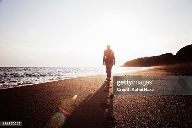 man shouldering a backpack walking in the beach - back lit people stock pictures, royalty-free photos & images