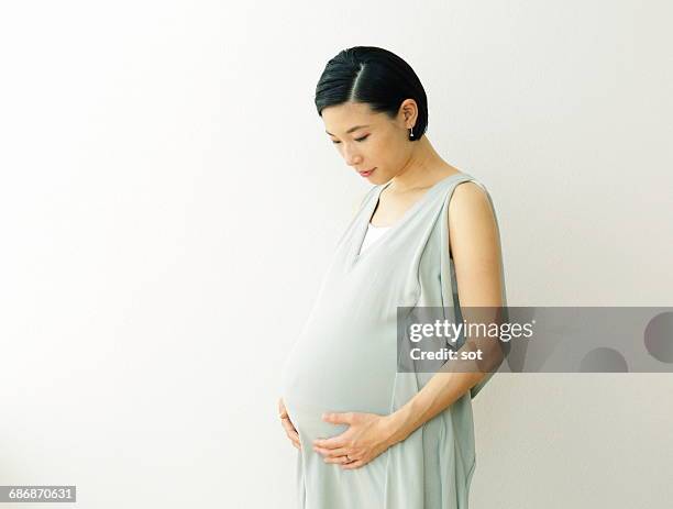 pregnant woman holding belly - asian woman pregnant stock pictures, royalty-free photos & images