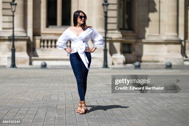 Sarah Benziane, fashion blogger, wears a Shein white off shoulder top, New Look blue denim jeans pants, New Look brown shoes, and sunglasses, on May...