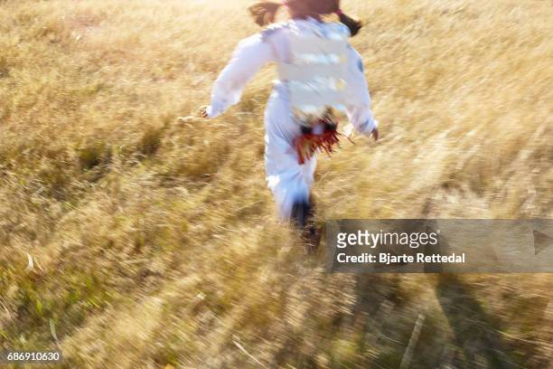 girl in astronaut suit with jet pack running through field - bjarte rettedal stock pictures, royalty-free photos & images