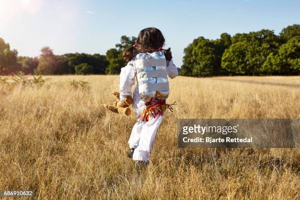 girl in astronaut suit with jet pack running through field - astronaut kid stock pictures, royalty-free photos & images
