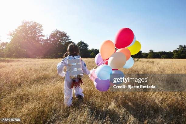 girl in astronaut suit with jet pack running through field - bjarte rettedal stock pictures, royalty-free photos & images